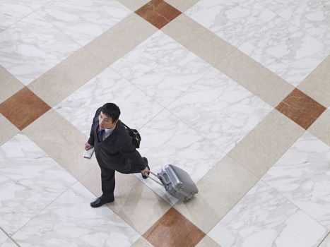 Elevated view of a businessman walking with suitcase on tiled floor