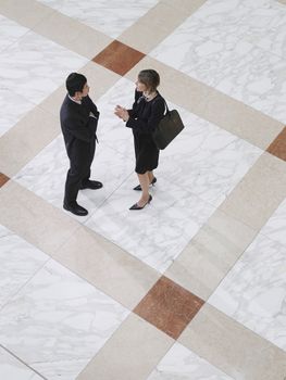 Elevated view of a businessman and woman talking on tiled floor
