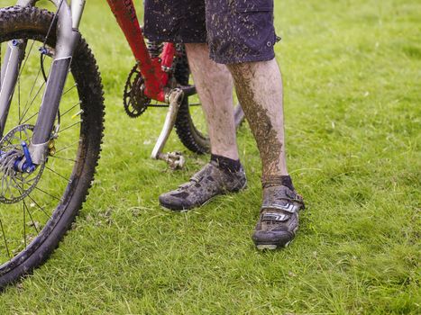 Muddy cyclist with bike outdoors