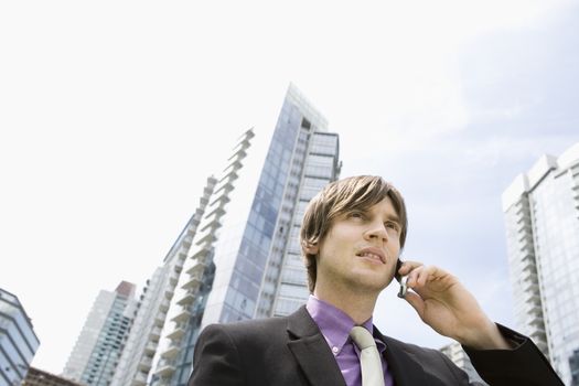 Young businessman using mobile phone outside office buildings