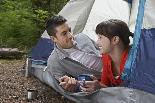 Couple with drinks lying in tent entrance
