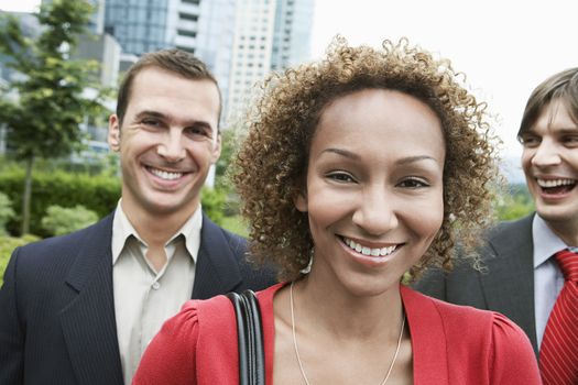 Two business men and woman smiling outdoors portrait