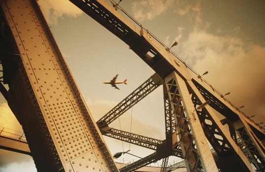 Airbourne passenger jet viewed through bridge superstructure