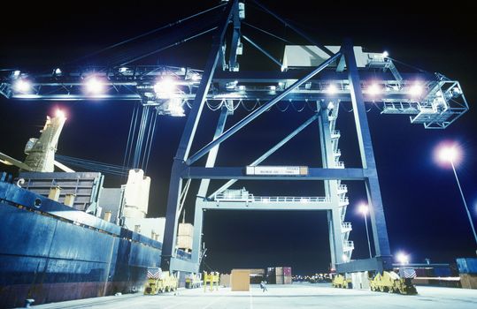 Crane loading container ship at night