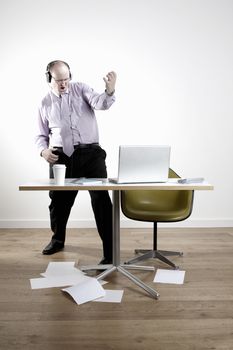 Businessman with earphones fooling around at desk