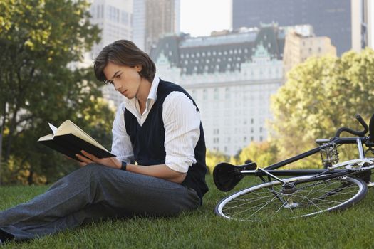 Man sitting on lawn reading book