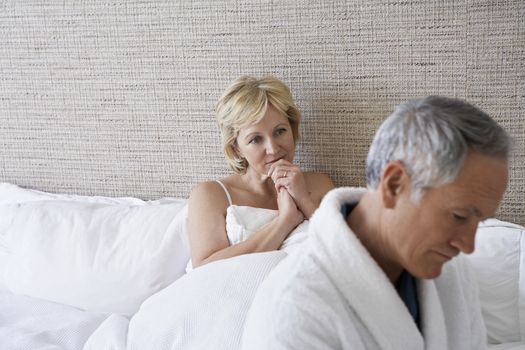 Unhappy middle aged couple in bedroom