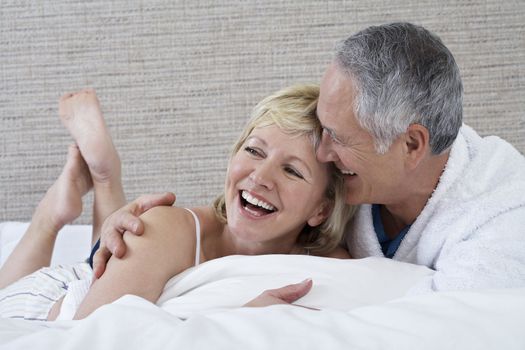 Cheerful middle aged couple lying in bed