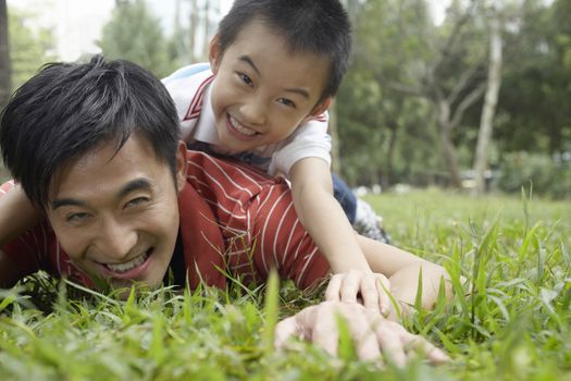 Playful father and son lying on grass at park