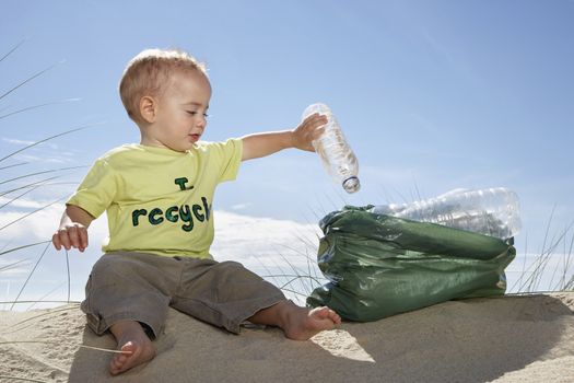 Boy (1-2) playing with plastic bottles on sand dune