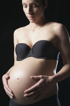 Pregnant woman touching abdomen studio shot