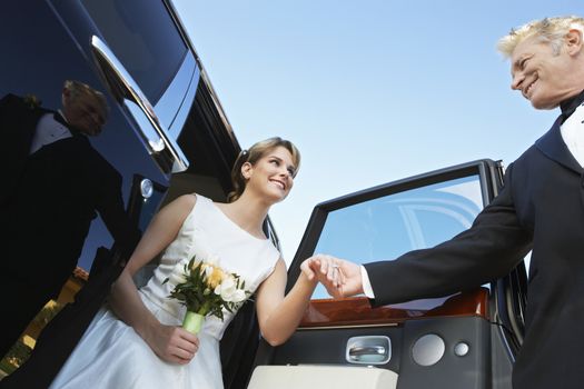 Father holding beautiful bride's hand as she gets down from car