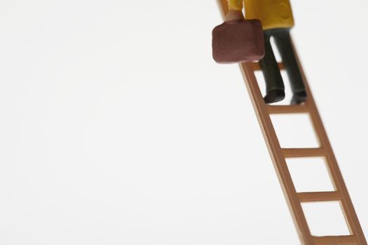 Low section of businessman figurine climbing ladder over white background