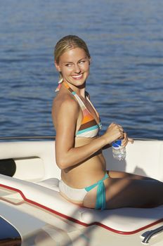 Happy young woman in bikini enjoying boat ride on lake