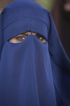 Portrait of a woman looking through blue face veil