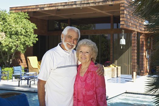 Portrait of a happy senior couple standing together outside house