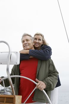Happy Caucasian couple at helm of sailboat