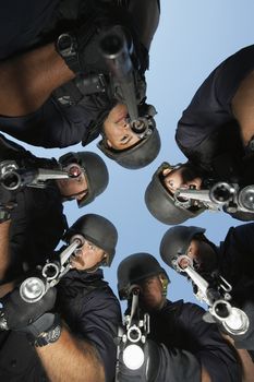 Group portrait of Swat officers standing in circle aiming guns
