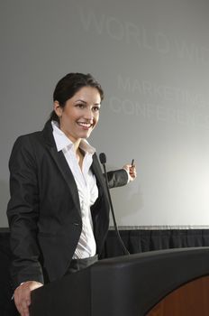 Happy businesswoman giving a lecture at podium