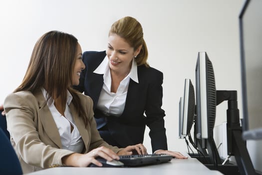 Two multiethnic businesswomen smiling over computers on table