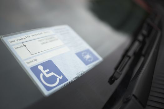 Closeup of handicap sticker on windshield of a car
