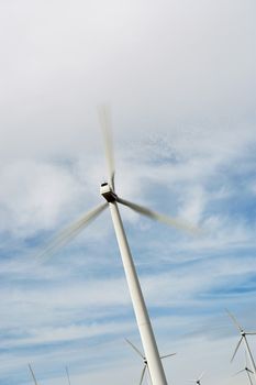 Wind turbine in motion against cloudy sky