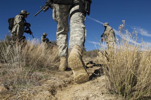 Low angle view of US army soldiers on a mission walking in desert