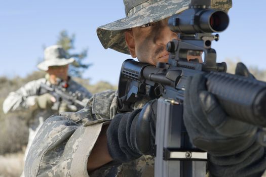 US army soldiers aiming rifles in field