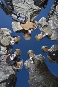 Low angle portrait of soldiers standing in circle aiming