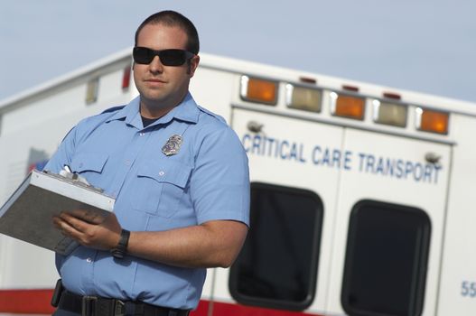 Portrait of a male paramedic writing notes in front of ambulance