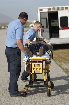 Paramedics carrying victim on stretcher by ambulance