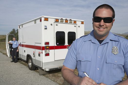 Portrait of a paramedic smiling in front of ambulance