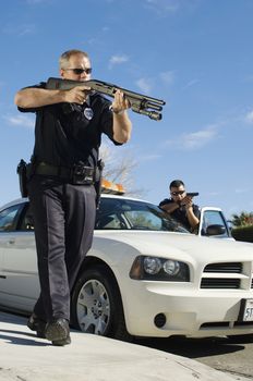 Full length of a two police officers aiming with guns