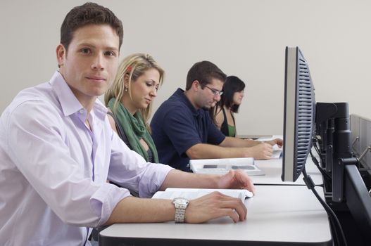 Portrait of male student with classmates in computer lab