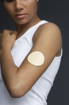 Closeup of woman with nicotine patch on arm over blue background