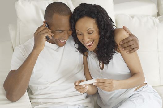 Couple excited with the pregnancy test results with man using mobile phone