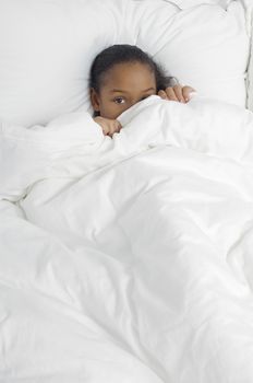 Portrait of an African American girl hiding under duvet