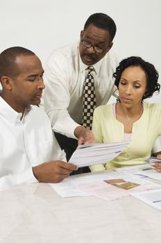 Financial advisor explaining plans to African American couple at desk in office
