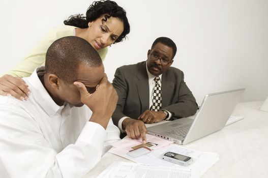 An African American woman consoling man with financial advisor pointing on credit cards at desk