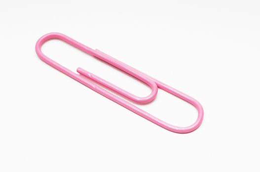 Closeup of pink paperclip over white background