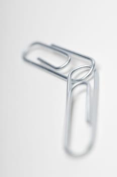 Detail of connected steel paperclips over white background