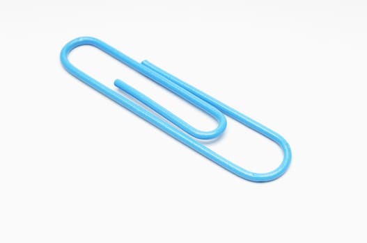 Closeup of blue paperclip over white background