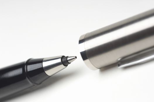 Cropped image of ballpoint pen with cap over white background