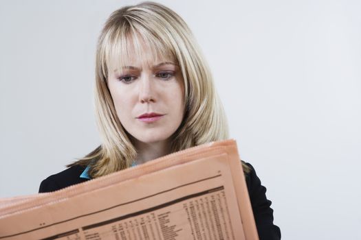 Caucasian businesswoman reading stock listings in newspaper isolated over white background
