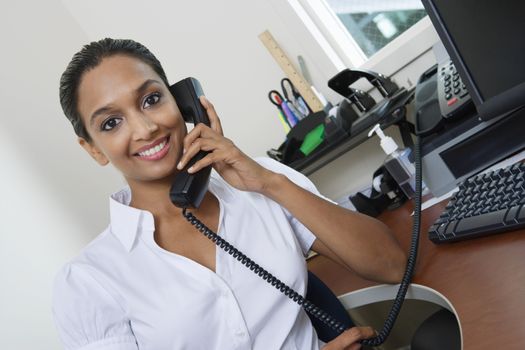 Portrait of an Indian business woman communicating on landline phone in office