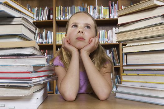 School girl sitting at desk with books in library