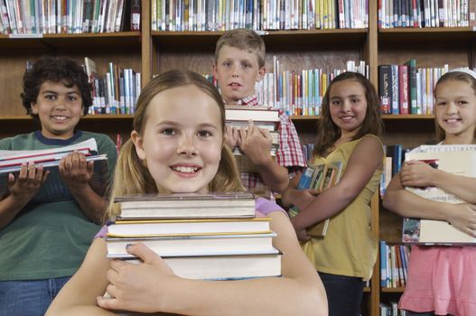 School children holding books in library portrait