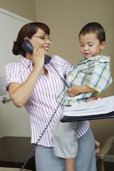 Business woman using phone with son at home