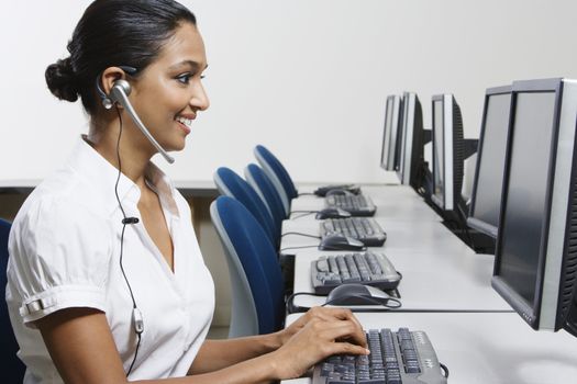 Side view of a happy beautiful customer service operator working in office