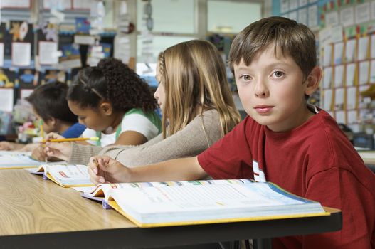 Schoolboy sitting in classroom and looking at camera